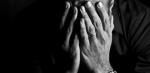 married man of color with hands over his face in mourning.