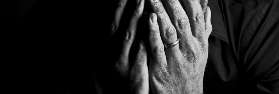 married man of color with hands over his face in mourning.